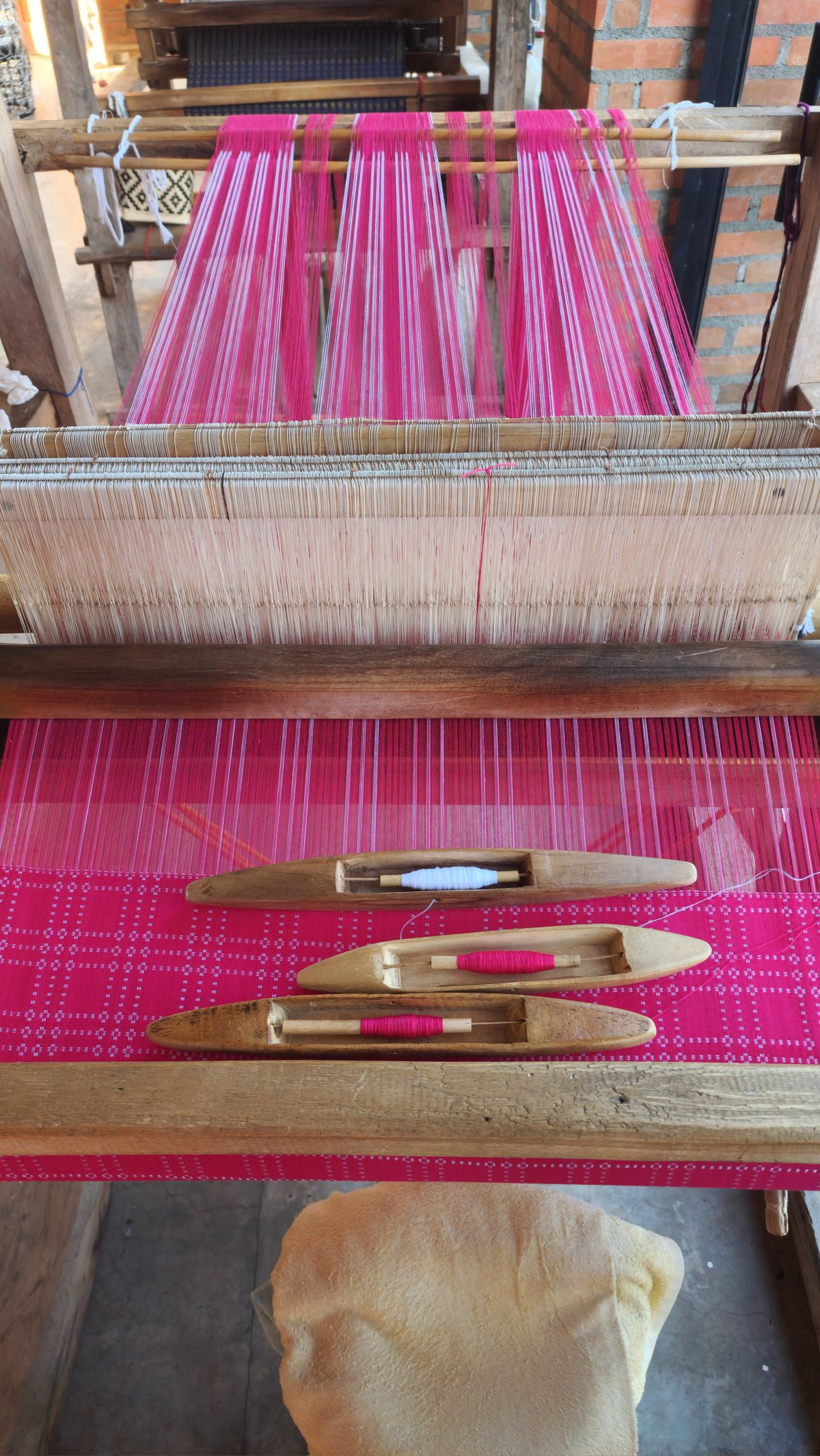 A half-finished pinilian textile still on the wooden loom at the weaving center.
